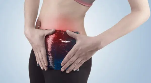 Femme appliquant une poche de glace sur sa zone douloureuse, symptomatique d'une pubalgie sans sport.