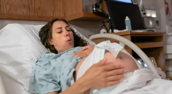 Femme en travail, le bébé engagé dans le bassin, respire profondément.