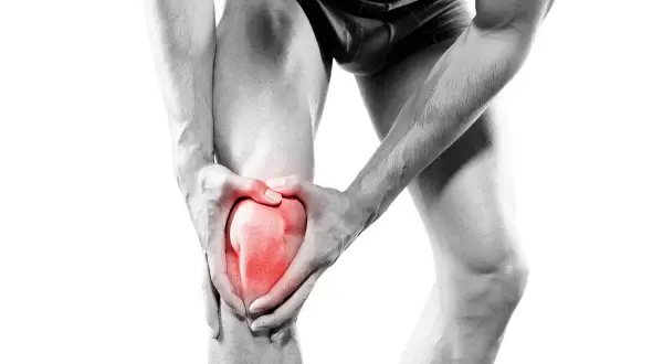 Homme tenant son genou, la rotule rouge vif symbolisant la douleur. Une image forte de la douleur rotule genou.