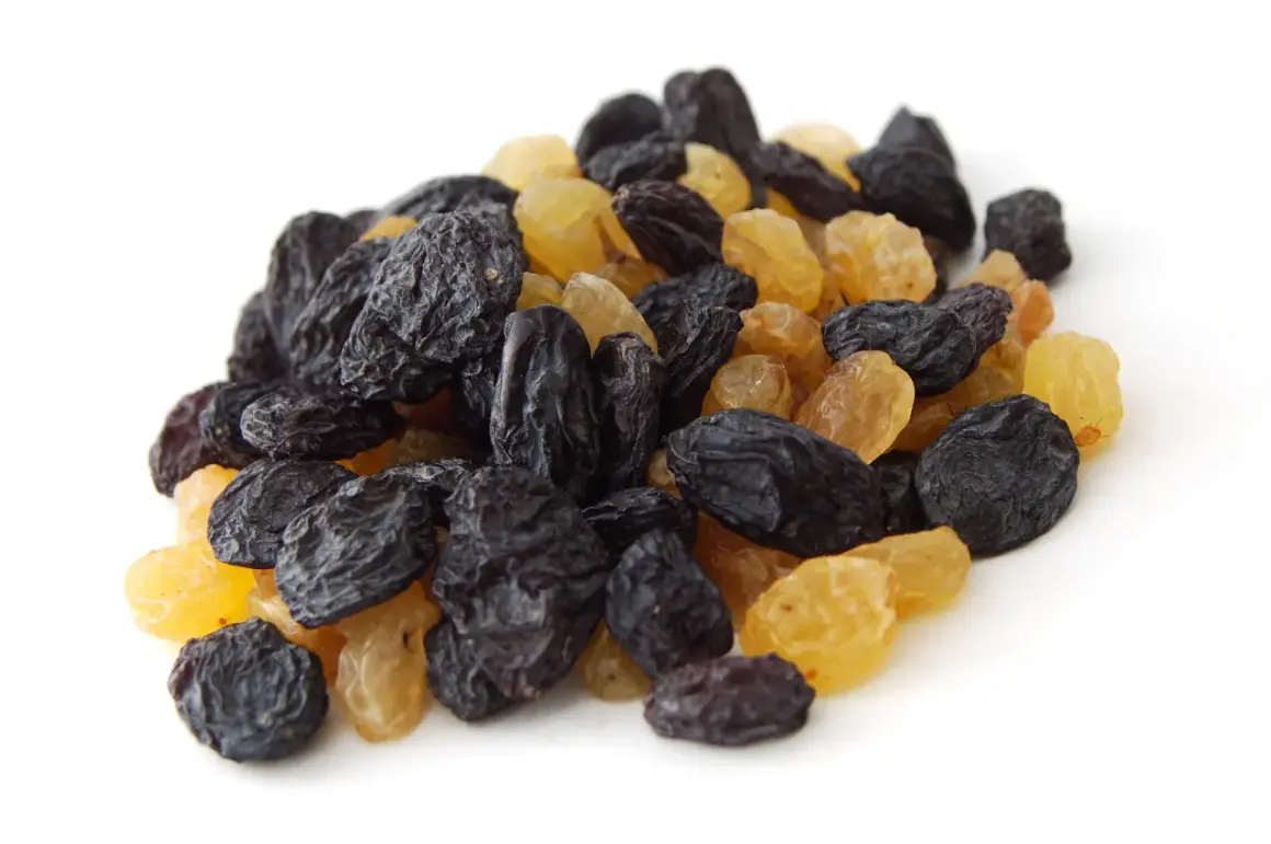 Un tas de raisins secs noirs et dorés, rappelant les méfaits du raisin sec sur la santé si consommés en excès.