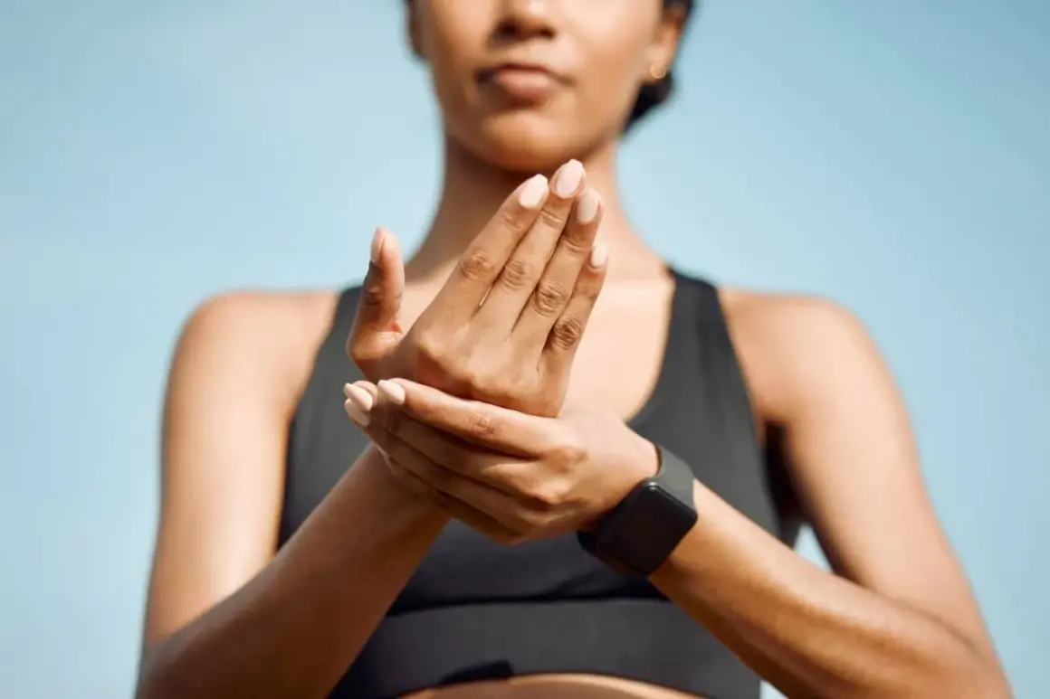 Une femme masse ses mains, peut-être à cause d'une douleur phalange doigt après un entraînement.