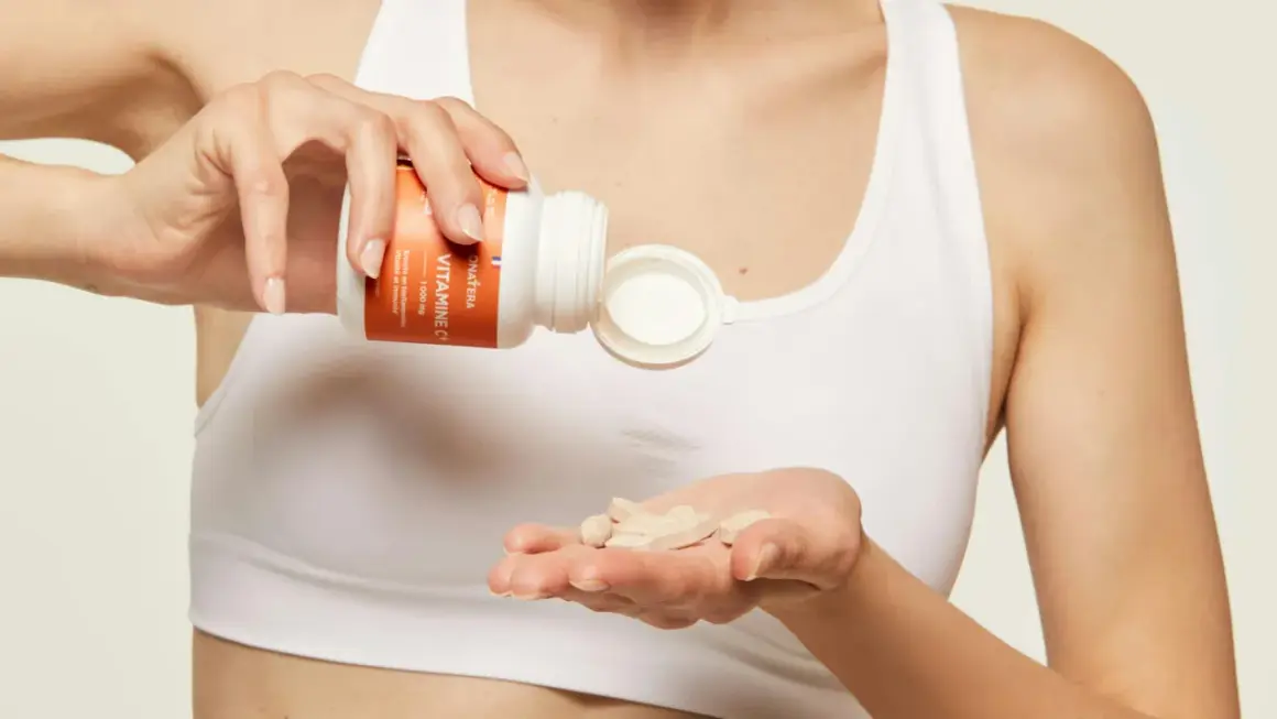 Une main verse des comprimés de vitamine C dans l'autre main, pour une cure de vitamine essentielle.