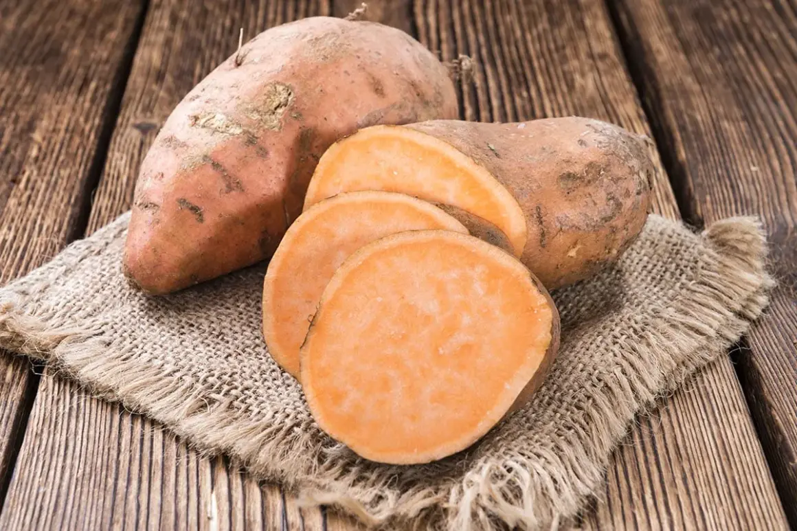 Patates douces entières et tranchées sur une toile de jute. Un aliment sain, faible en calories, parfait pour une alimentation équilibrée.