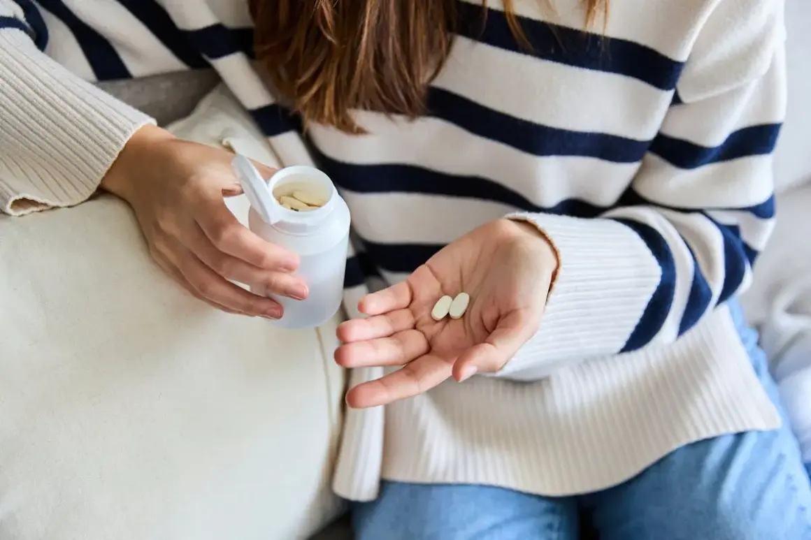 Une femme tient des comprimés dans sa main, peut-être pour lutter contre la fatigue. Le collagène est une option.