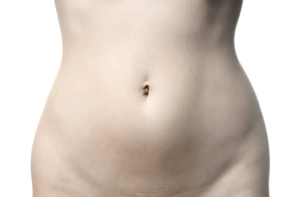 Le ventre d'une femme, avec son nombril et la zone du pubis, sur fond blanc.