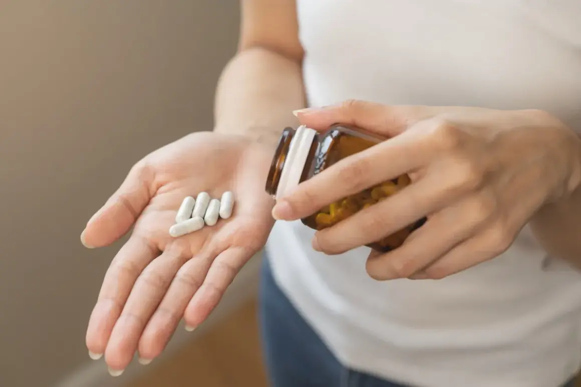 Main tenant une pilule dans sa paume, une personne verse des capsules d'un flacon. Une cure de vitamine D pour le bien-être.