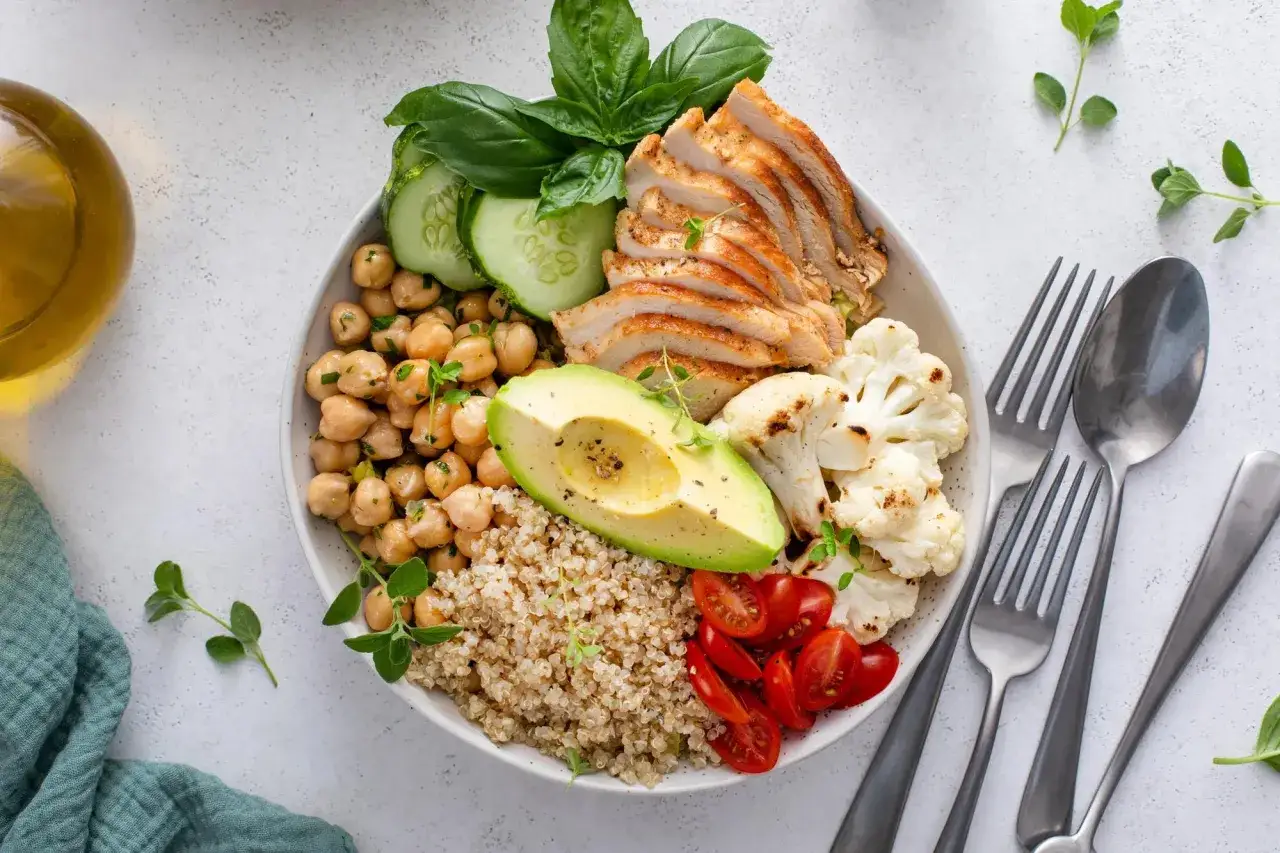 Un bol coloré avec poulet, pois chiches, avocat, quinoa et légumes. Un aliment bon pour les cheveux et ongles, plein de nutriments.