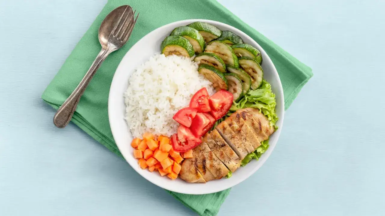 Assiette de poulet grillé, riz blanc, courgettes grillées, tomates et carottes. Un repas sain et équilibré, idéal pour les aliments pauvres en fodmap.