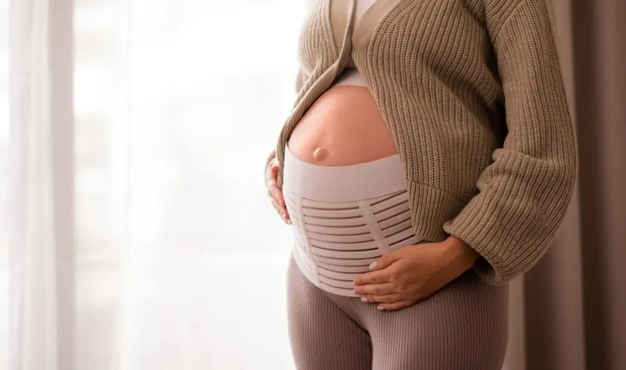 Ventre rond d'une femme enceinte portant une ceinture de grossesse à partir du 4ème mois pour soulager le dos.