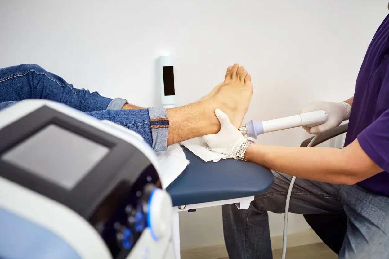 Un patient reçoit un traitement par ondes de choc pour son pied. Bien que souvent bénéfiques, il faut connaître les inconvénients des ondes de choc.