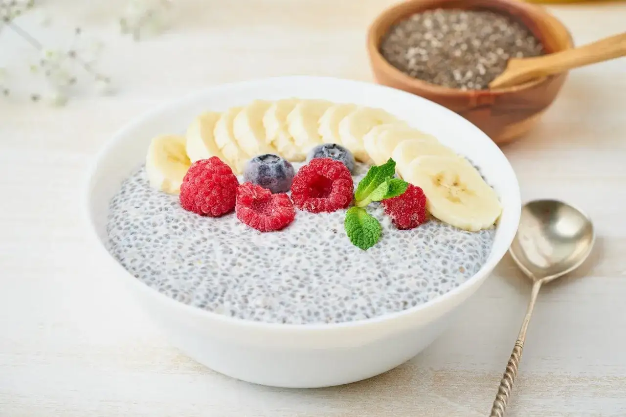 Un bol de pudding de graines de chia, garni de framboises, myrtilles et bananes. Un délice sain pour une femme enceinte.
