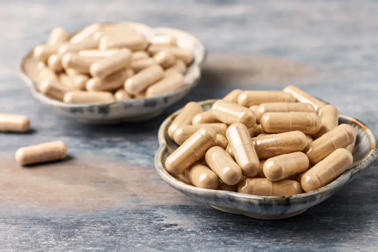 Gélules d'ashwagandha dans des bols. Pourquoi ashwagandha interdit en France ? La question se pose face à ces compléments.