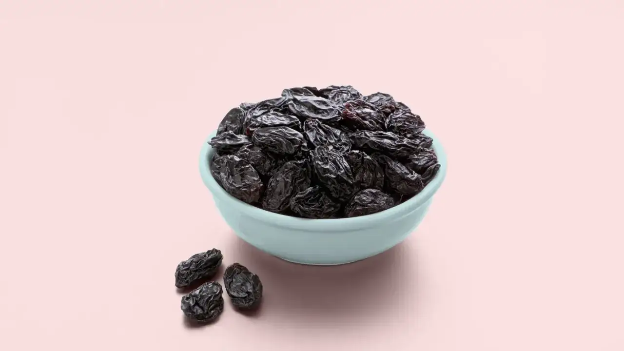 Un bol rempli de raisins secs fonc&eacute;s, quelques-uns &eacute;parpill&eacute;s &agrave; c&ocirc;t&eacute;. Attention aux m&eacute;faits du raisin sec, trop sucr&eacute; !