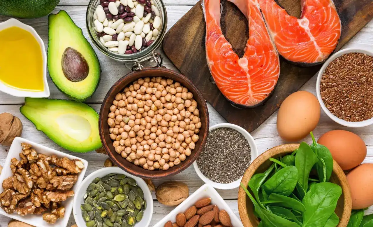 Assortiment d'aliments sains pour les cheveux : saumon, avocat, œufs, noix, graines, pois chiches, épinards et huile.