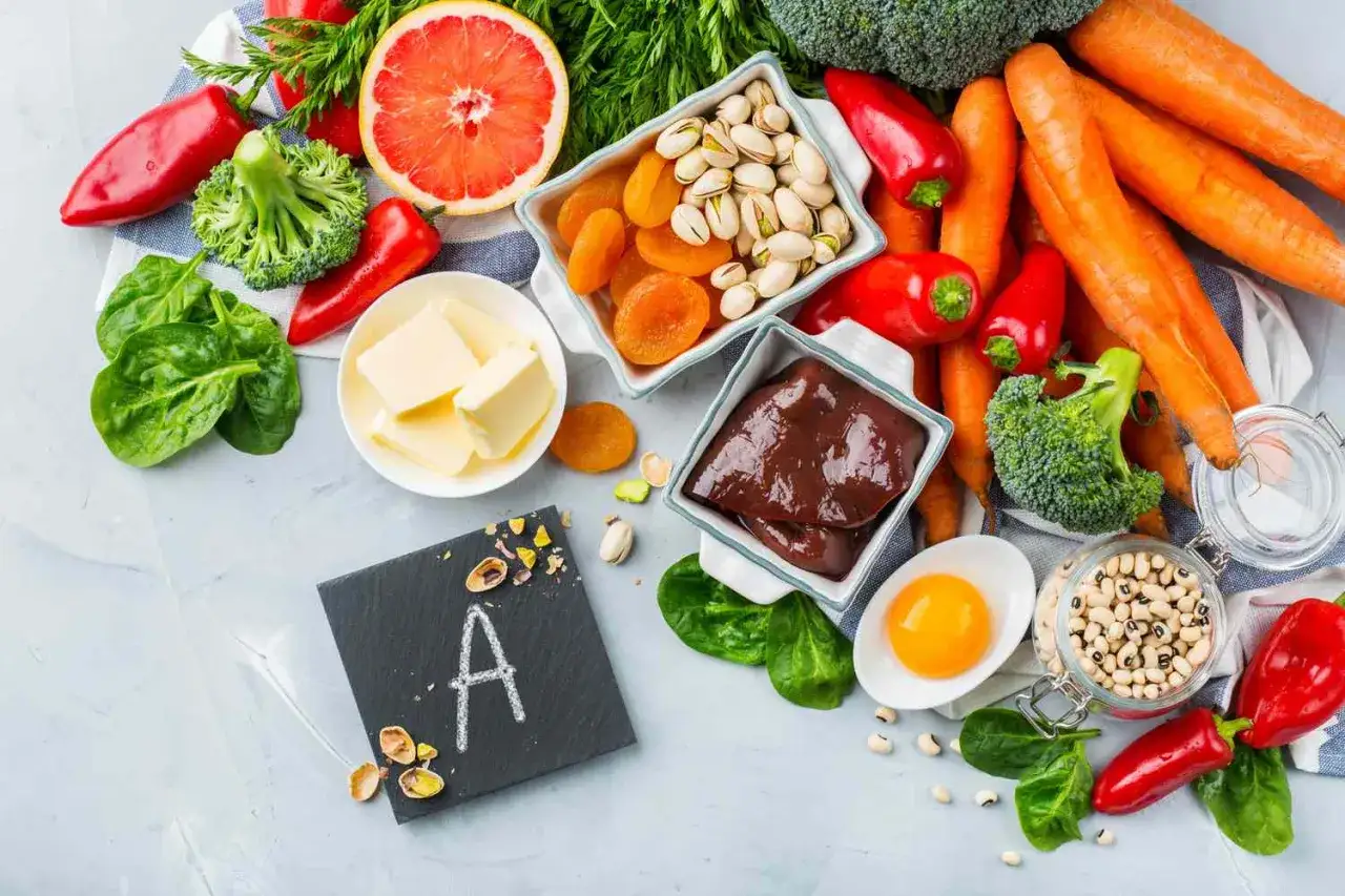 Assortiment d'aliments riches en vitamine A : foie, carottes, épinards, œufs, abricots secs, poivrons, brocolis, pistaches, haricots blancs et beurre.