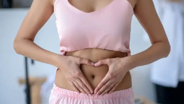 Femme faisant un cœur avec ses mains sur son ventre, soulageant un tiraillement bas ventre.