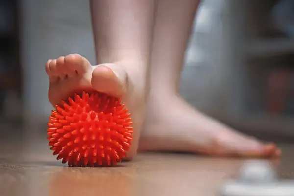 Un pied utilise une balle rouge texturée pour soulager une tendinite sous le pied.