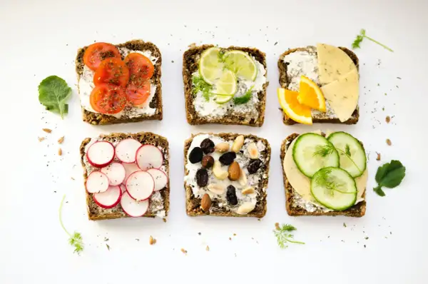 Six tartines variées : tomates, radis, agrumes, fromage, fruits secs et concombre. Un menu type femme 50 ans, sain et coloré.
