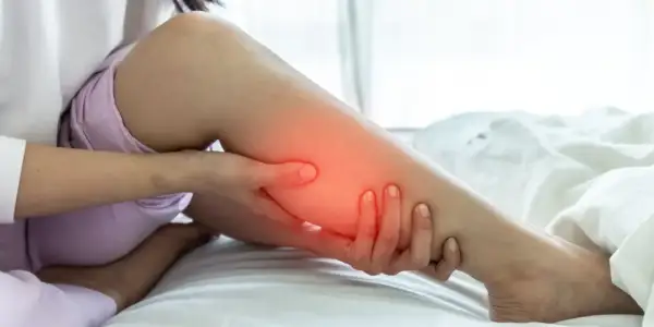 Une personne se tient la jambe, le mollet dur et gonflé, avec une zone rouge indiquant la douleur.