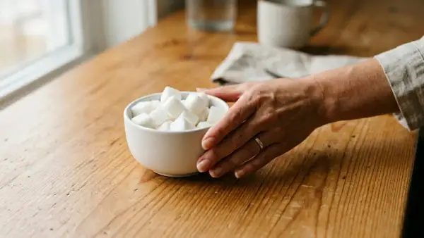 Main tenant une coupe de sucre, une main se prépare à comment se sevrer du sucre.