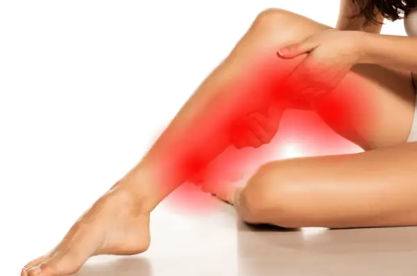 Femme se tenant la jambe, zone rouge indiquant la douleur. Des conseils pour comment soulager une sciatique.