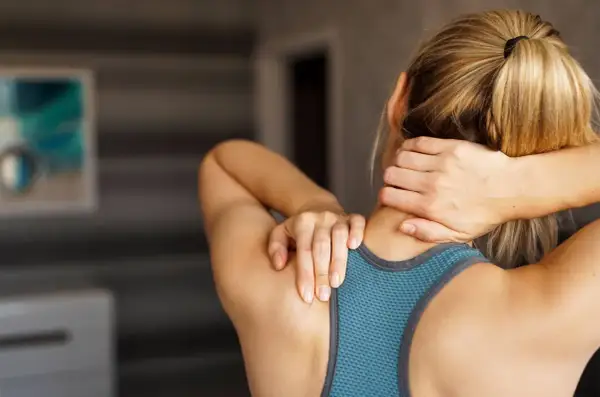 Femme se tenant le cou, souffrant de muscles du cou douloureux après une longue journée.