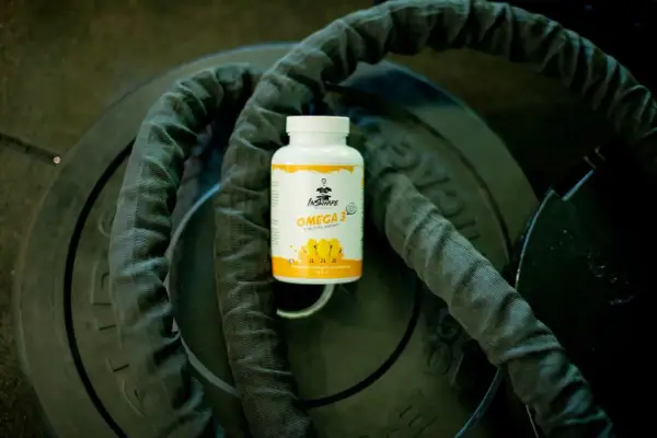Bouteille d'oméga 3 sur des poids de musculation, idéale pour le bien-être, matin ou soir.