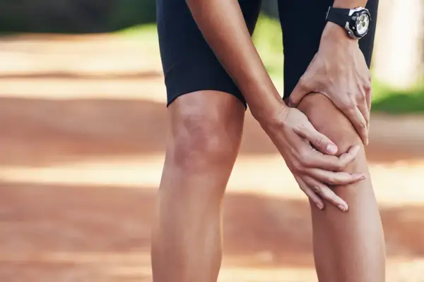 Une athlète se tient le genou, peut-être une douleur au ligament croisé du pied.