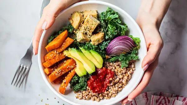 Un bol coloré avec patates douces, avocat, tofu, chou kale et oignon rouge. Une délicieuse alimentation anti cholestérol.