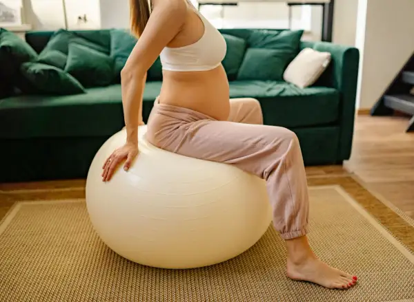 Femme enceinte assise sur un ballon de gym pour un exercice d'ouverture du col.