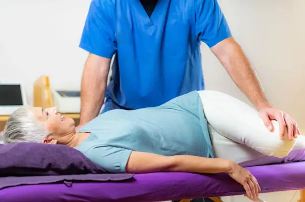 Un kinésithérapeute aide une femme à faire un exercice pour soulager sa tendinite fessière.