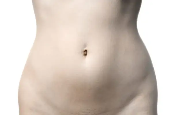 Le ventre d'une femme, avec son nombril et la zone du pubis, sur fond blanc.