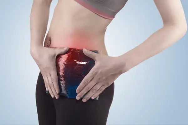 Femme appliquant une poche de glace sur sa zone douloureuse, symptomatique d'une pubalgie sans sport.