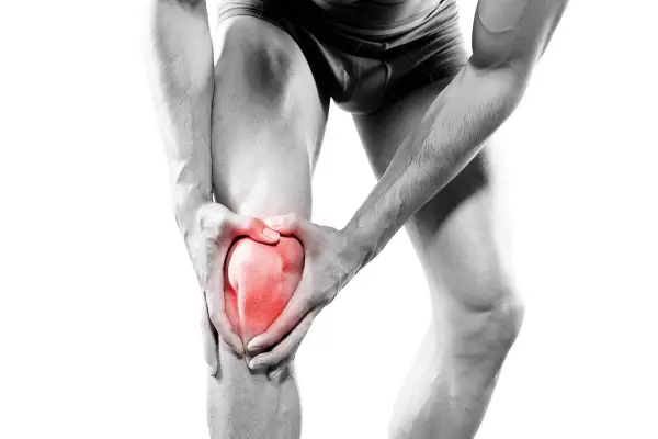 Homme tenant son genou, la rotule rouge vif symbolisant la douleur. Une image forte de la douleur rotule genou.